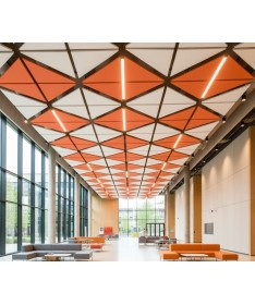 Suspensions acoustiques Triums orange et blanches formant un plafond géométrique dans un grand hall lumineux.