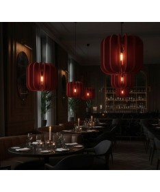 Luminaires acoustiques Iluro rouges suspendus dans un restaurant élégant à l’ambiance feutrée.