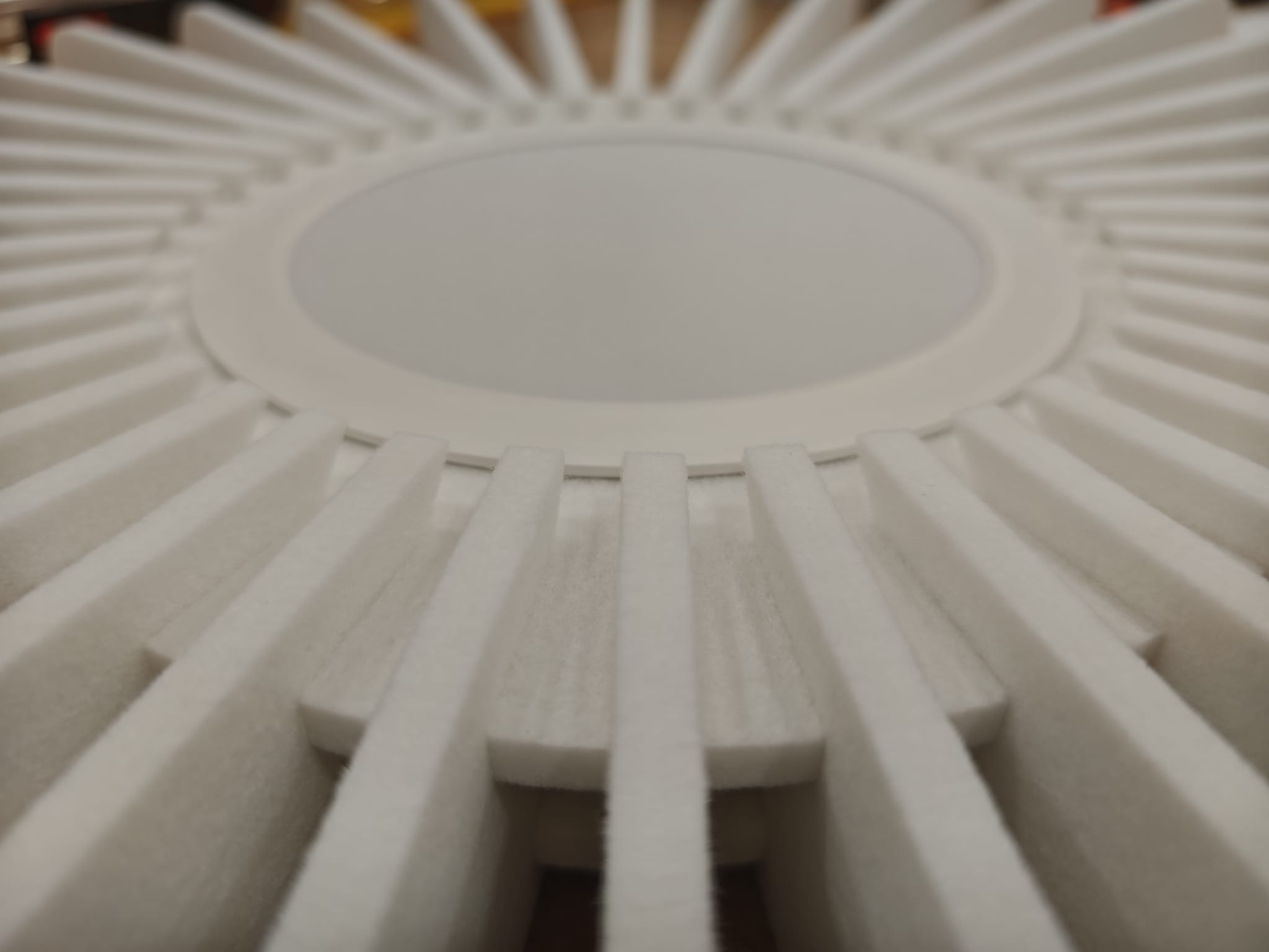 Gros plan latéral d'un luminaire Solea : on distingue les lamelles individuelles en feutre PET, leur épaisseur uniforme et la texture fibreuse caractéristique du matériau.